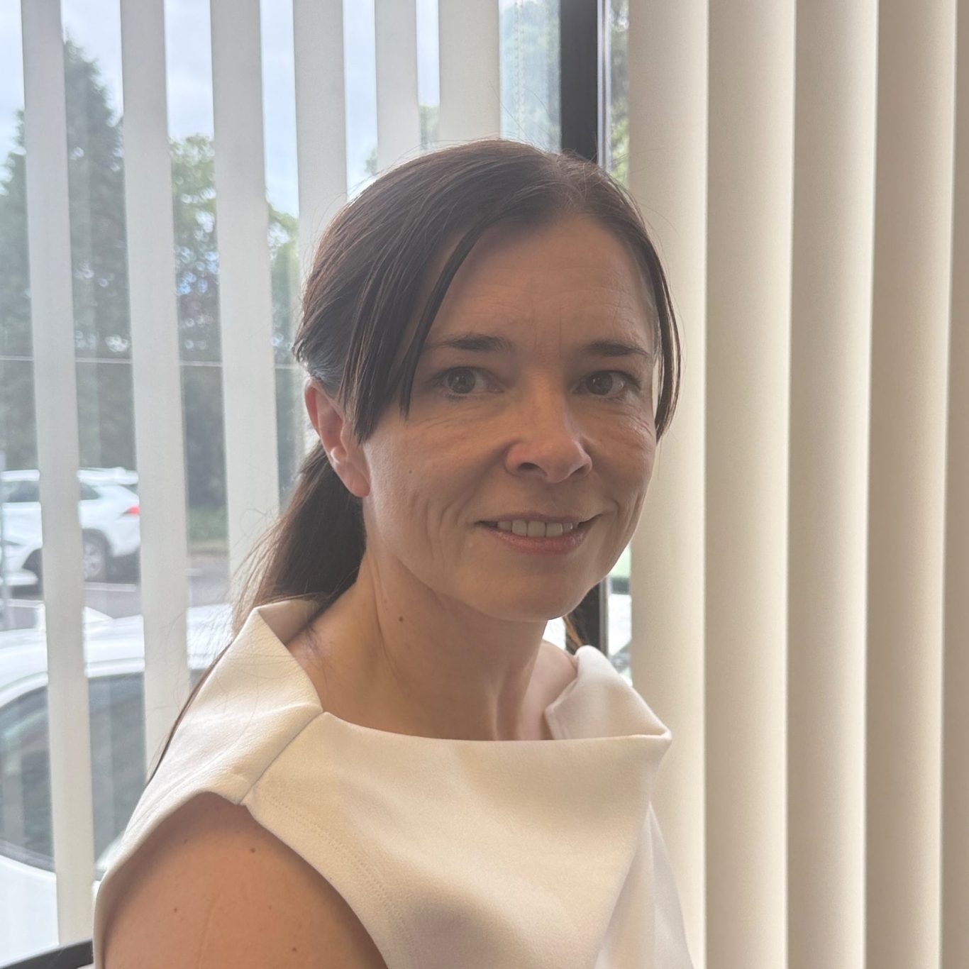 Porträt von Anja Kuffel mit langen, dunklen Haaren und freundlichem Lächeln, in Schwarz-Weiß.